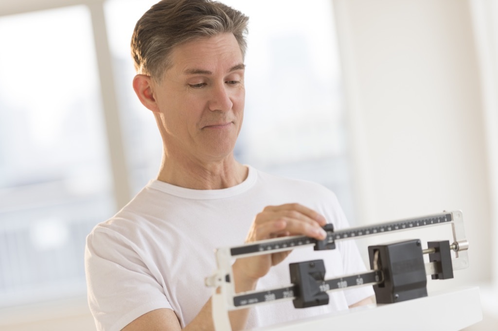 middle aged white man checks weight on scale