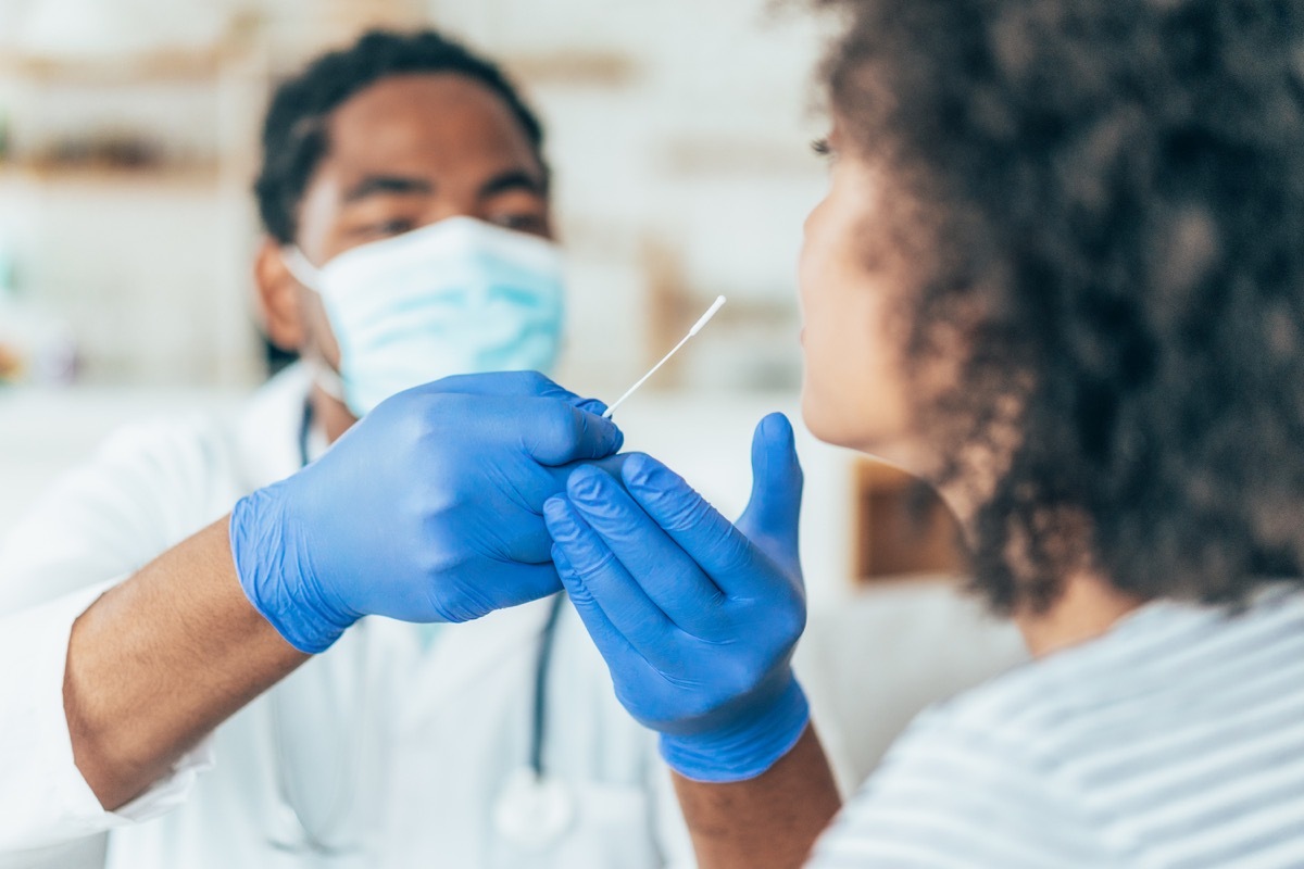 Doctor with protection gloves doing Coronavirus nasal swab test on young female patient