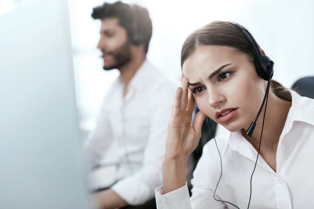 young female customer service rep looks annoyed while using headset, things never to say to customer service rep