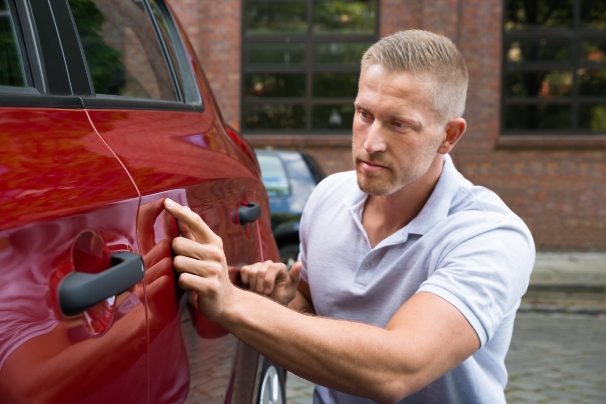 man looking for scratches on car