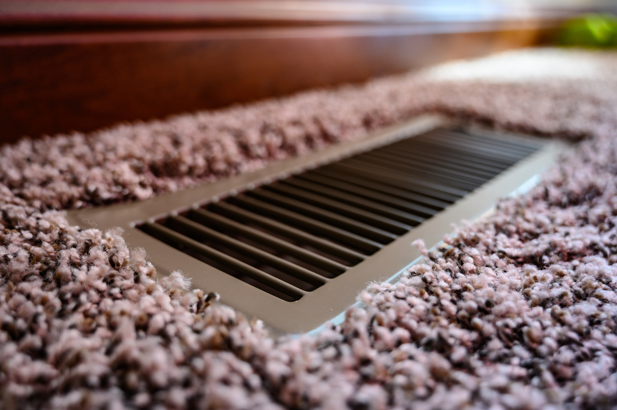 Focus on floor vent in room with carpet