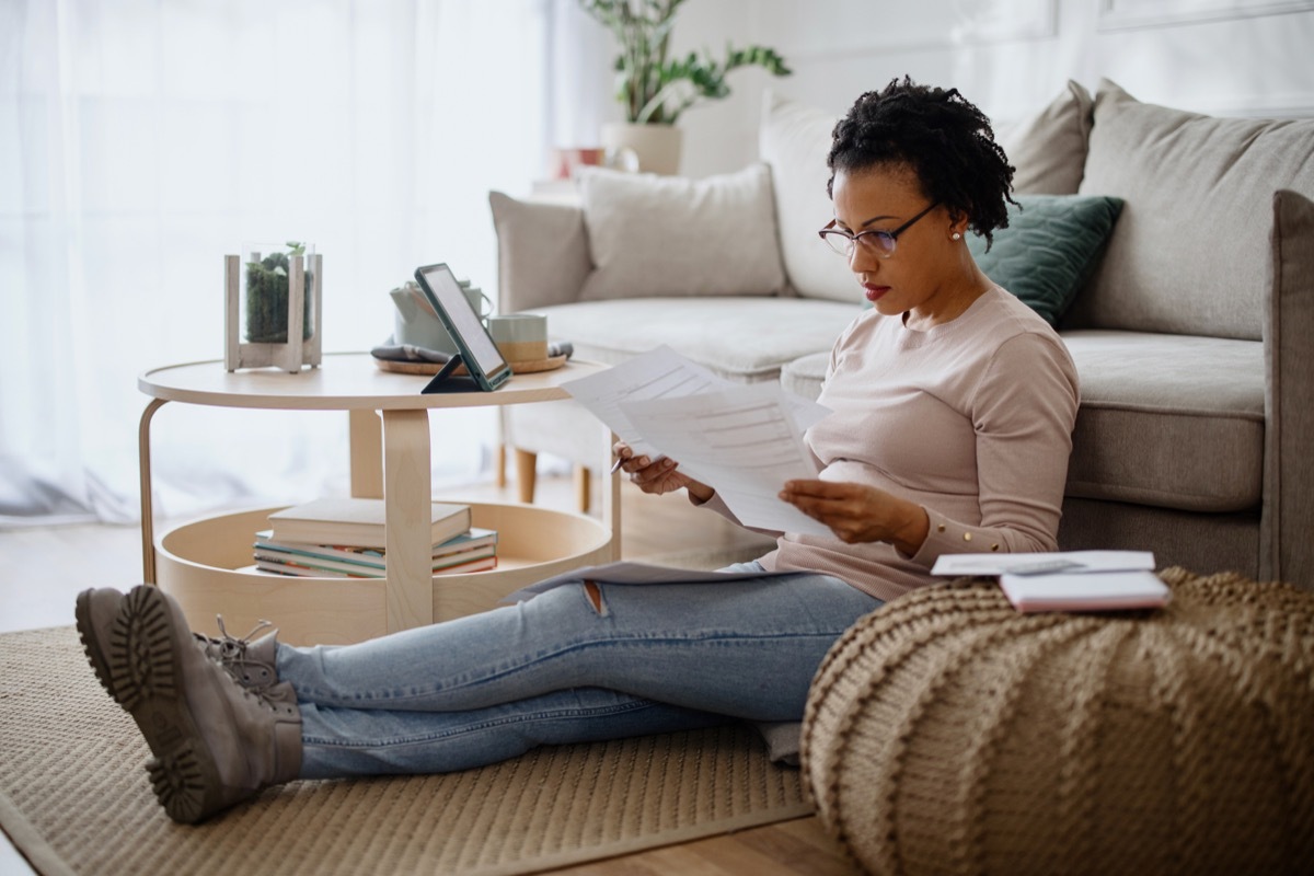 Woman using a digital tablet and going through paperwork while working from home