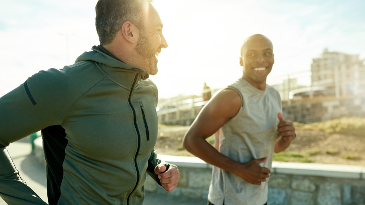 white man and black man running outside and smiling at each other