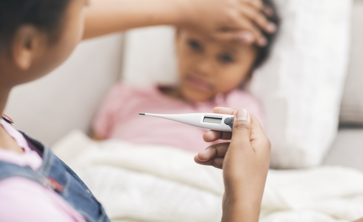 girl touching her sick little sister's forehead, checking temperature